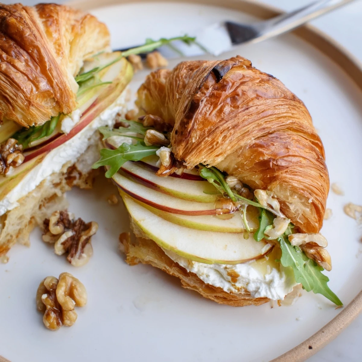 Close-up of Apple Goat Cheese Croissant Sandwich with creamy filling and crunchy walnuts