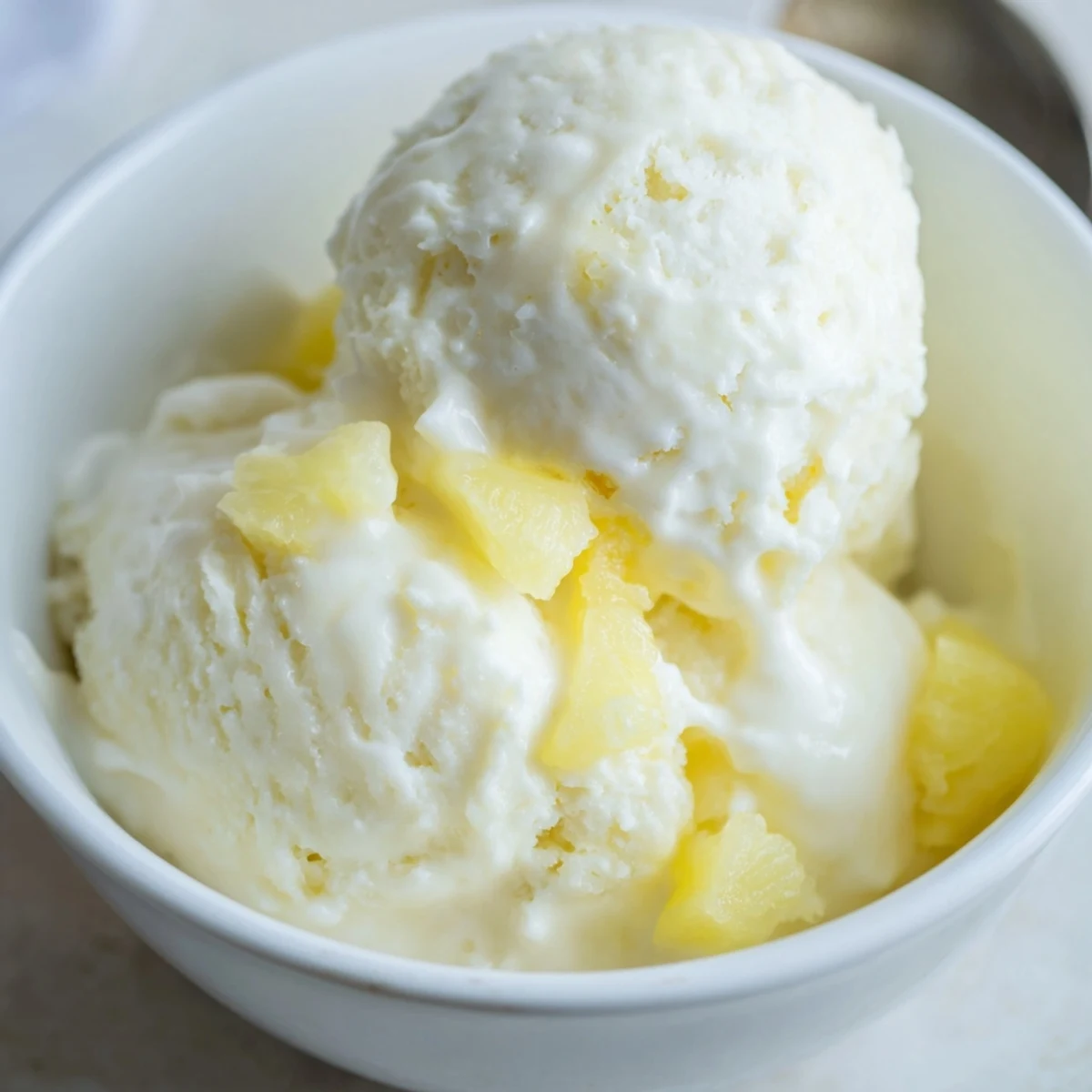 Homemade Creamy Pineapple Ice Cream Recipe topped with toasted coconut, chilled scoops