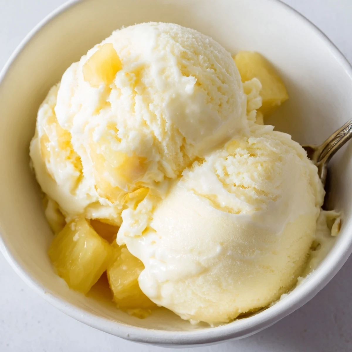 Velvety Creamy Pineapple Ice Cream melting slightly on cone, bright citrus tang