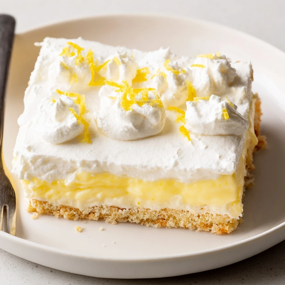 Slice of Lemon Lush Cake on plate, fluffy topping and tangy aroma