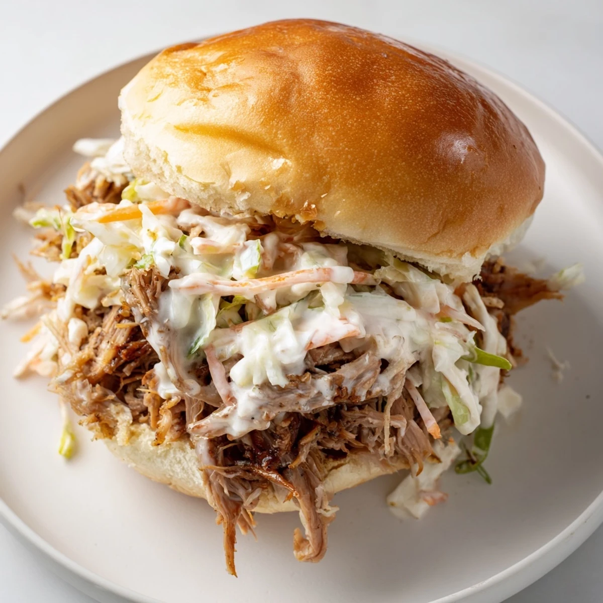 Juicy pulled lamb shoulder glazed in creamy Alabama white sauce on soft slider rolls