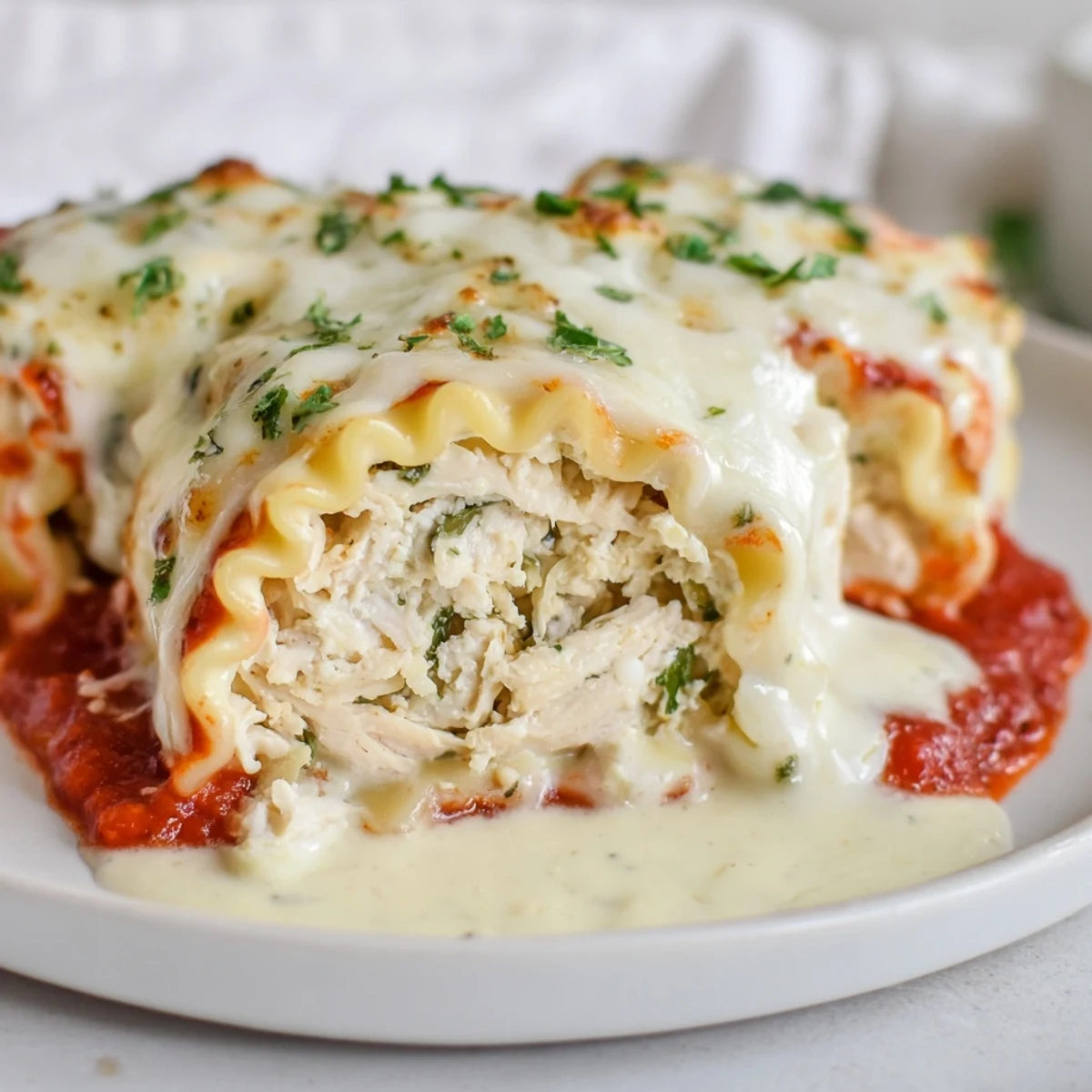 Tender Garlic Parmesan Chicken Lasagna Roll Ups served on a white plate with parsley