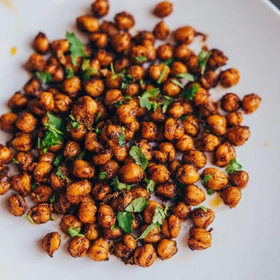 A close-up of Spicy Roasted Chickpeas with Cumin and Chili Powder reveals a crispy texture, perfect for topping a fresh garden salad.