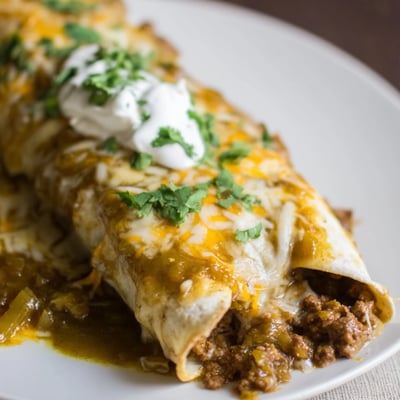 Freshly baked Beef Enchiladas with Green Chili Sauce served with sour cream on the side.