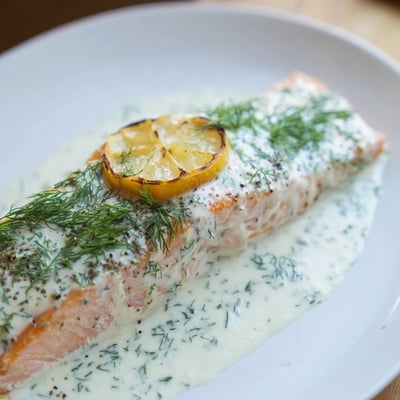 Flaky Baked Salmon with Dill Sauce is served alongside bright green asparagus and roasted red potatoes.