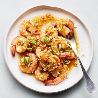 Close-up of High Protein Honey Garlic Shrimp garnished with fresh green onions and sesame seeds.