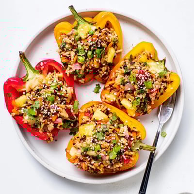 A single teriyaki pineapple chicken and rice stuffed pepper rests on a plate, revealing a fluffy filling of tender chicken and sweet pineapple.