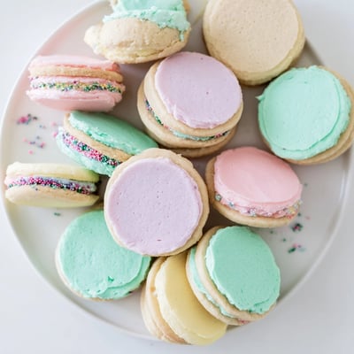 Golden-edged Pastel Sugar Cookie Sandwiches displayed on a white ceramic plate, ready for spring gatherings.