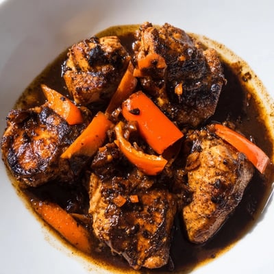 Jamaican brown stew chicken served over steamed white rice with thick, deeply flavored sauce
